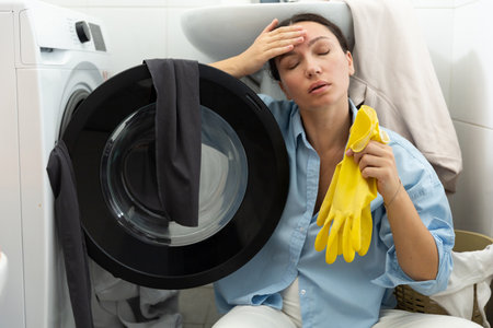 A tired housewife sits by the dirty laundry. Domestic routine and womens work.の写真素材