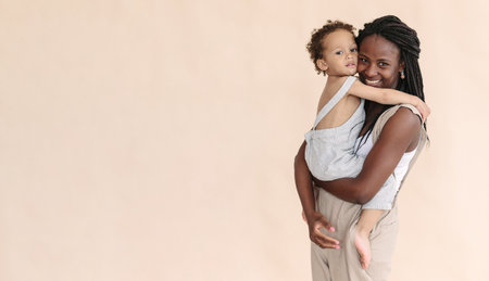 African-American mother with baby smiles and rejoices on beige background Minimalist portraits, space for textの写真素材