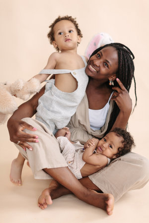African-American baby and child with mother on a beige background in the style of minimalismの写真素材