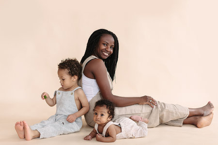 African-American baby and child with mother on a beige background in the style of minimalismの写真素材