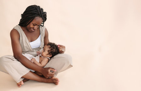 African-American mother with baby on beige background Minimalist portraits, space for textの写真素材
