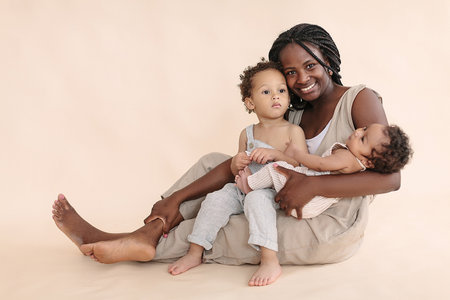 African-American baby and child with mother on a beige background in the style of minimalismの写真素材