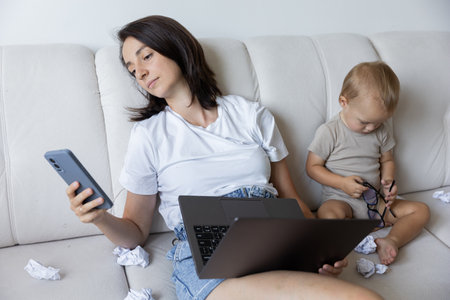 a young girl mom is trying to work at home with a baby. Procrastination at work.の写真素材