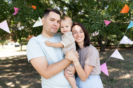 young parents with a child celebrate a holiday in nature against the background of decorの写真素材