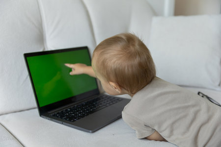 A little boy works on a laptop, presses buttons in a room at home. A small programmer, the concept of early development and online education.の写真素材