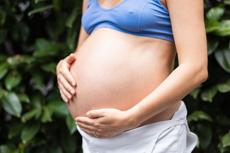 Beautiful big belly pregnant girl on the background of greenery and leaves, healthy pregnancy and childbirthの写真素材