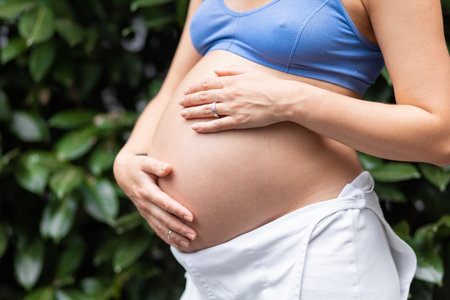 Beautiful big belly pregnant girl on the background of greenery and leaves, healthy pregnancy and childbirthの写真素材