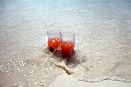 Two glasses with drinks are located on the sandy seashoreの写真素材