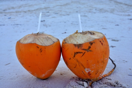 Two cocoes with drinks are located on the sandy seashoreの写真素材