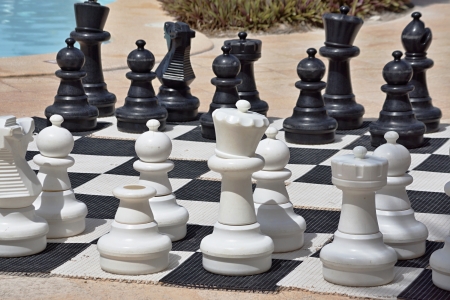 Big black and white figures for game in chess on a beach during restの写真素材