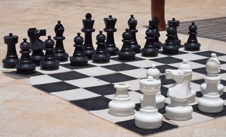 Big black and white figures for game in chess on a beach during restの写真素材
