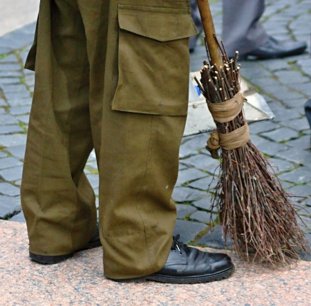 The cleaner sweeps with a broom a stone pavementの写真素材