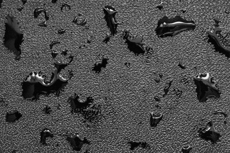 Black leather fabric with various oil slicks for a textural abstract background