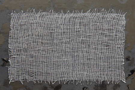 Piece of a white gauze on black skin with oil drops for the textured abstract background