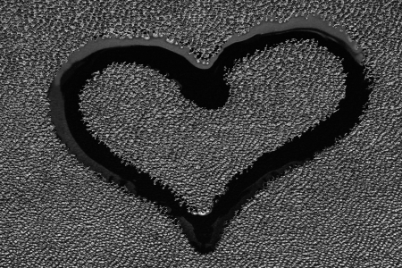 Sign of a symbol of love - a heart in the form of a wet spot on black tissue of skin closeupの写真素材