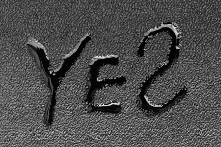 The word "YES" on black skin is written by a liquid closeupの写真素材