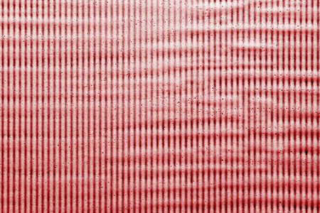 abstract texture of soap suds of red crimson color on a striped dark backgroundの写真素材