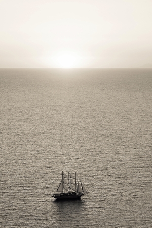 sea landscape with a sunset of beige color on the horizon and one sailboat or the yacht on waterの写真素材