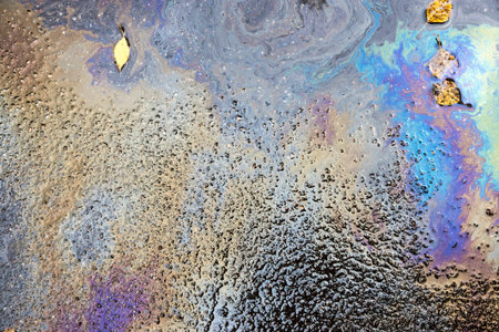 abstract brilliant spotty pattern from iridescent spots of oil or gasoline on wet autumn asphalt of...