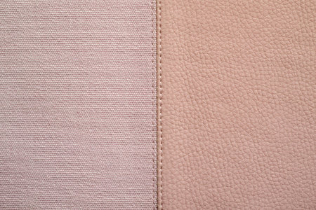 the stitched combination of two textures of pink color from rough fabric and an imitation leather for abstract backgroundsの写真素材