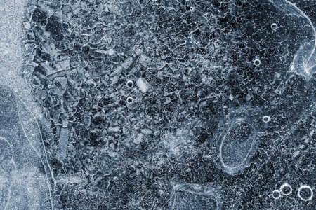 abstract surface of ice of dark-blue color with bubbles and with scratches