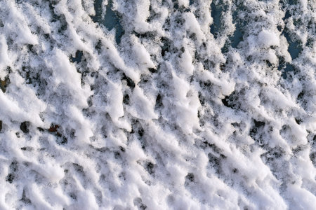 abstract bumpy texture of white snow on dark glass
