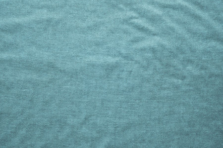 rough texture of the wavy crumpled fabric of turquoise color with a dense mesh interlacing of...