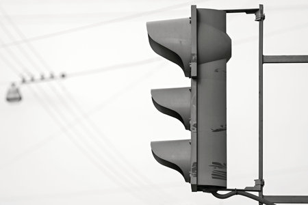 the alarm traffic light of gray color against the sky with electric wires and the lamp