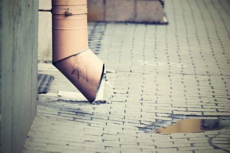 digital photo of a drainpipe and pool on a stone blocks in the old yard or the lane of the old city with effect of retroの写真素材