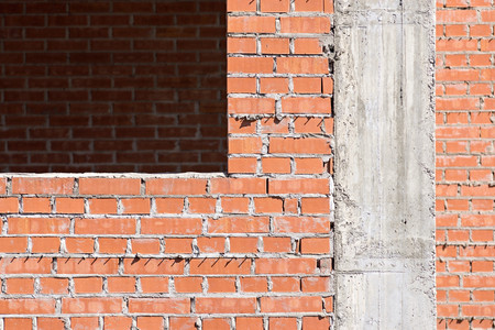 brick wall under construction with a window opening and concrete part of a columnの写真素材