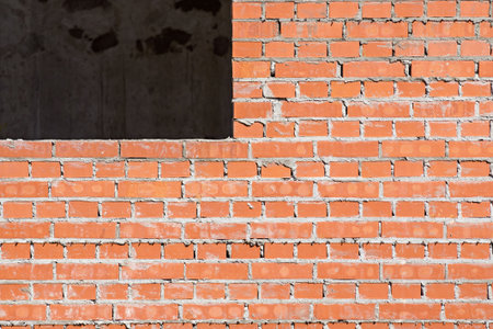 red brick wall under construction with a window opening for the abstract textured backgroundsの写真素材