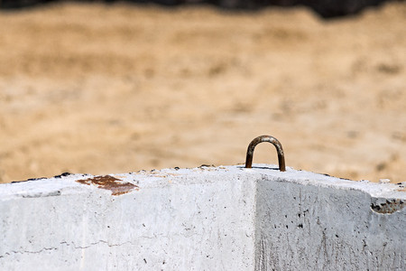 old rusty iron bracket for assembly of a construction concrete design on an indistinct sandy backgroundの写真素材