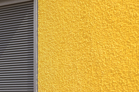 the abstract textured background of a rough concrete wall and iron blinds of yellow gray colorの写真素材