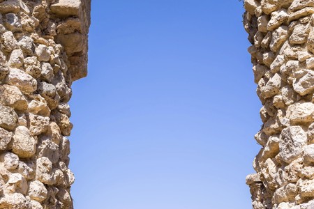 architectural part of ancient fortress with stone columns of an aperture for pass against the clear and clear blue skyの写真素材