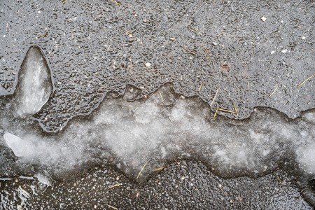 slush or heap of damp snow of an abstract form on an asphalt surface of natural dirty colorの写真素材