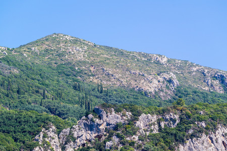 stone hills or mountains with wild thickets against the blue clear sky and a blank space for the textの写真素材
