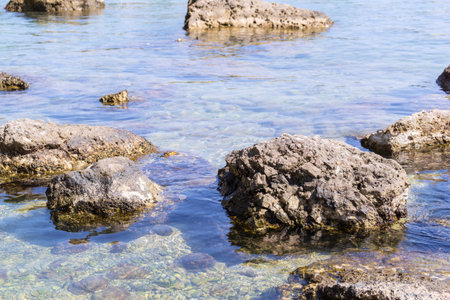big stones boulders lie in transparent water of the sea coast for natural abstract toneの写真素材
