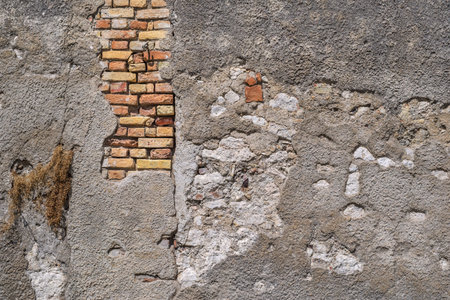 old brick wall with the destroyed plaster for the textured vintage background and wallpaper