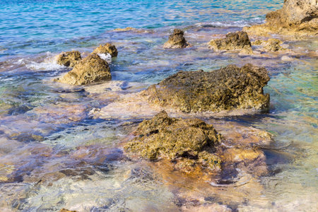 the wild sea coast with big rocky stones and transparent waterの写真素材