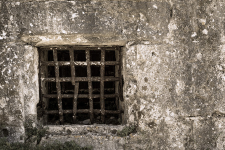 window grate from old rusty iron on a stone wall of ancient prison or a dungeonの写真素材