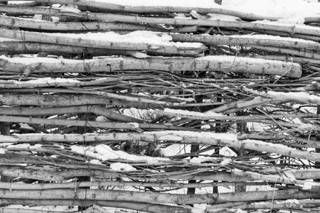 snow-covered wattle or fence from wooden branches of monochrome tone for the natural textured backgroundの写真素材