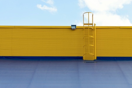 part of an industrial structure or warehouse of a hangar with a roof and a ladder closeup against the cloudy skyの写真素材