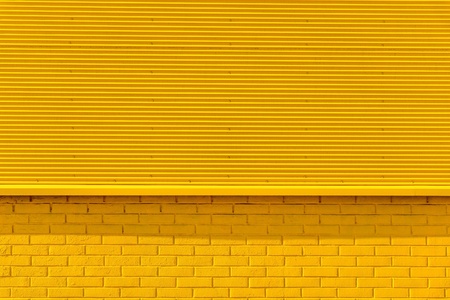 the textured background from corrugated iron and a brick of yellow color and a blank space for the textの写真素材