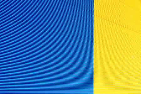 the textured background from corrugated iron of yellow and blue color and a blank space for the textの写真素材