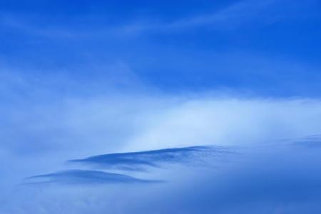 the blue cloudy sky with a separate cloud of an abstract form for a natural backgroundの写真素材