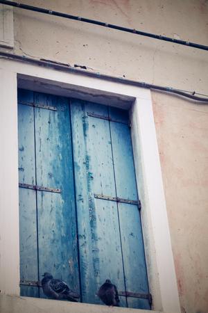 old facade of the ancient building with a window and the closed sun blind in retro styleの写真素材