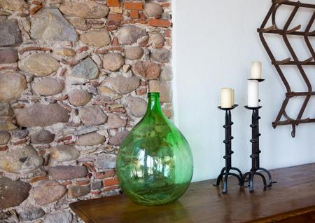 fragment of a room interior with a glass vase and with forged candlesticks a closeup and a stone wallの写真素材