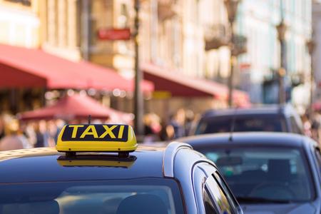 the yellow symbol or sign with an inscription of a taxi is located on a car roof on an indistinct background city and blank spaceの写真素材