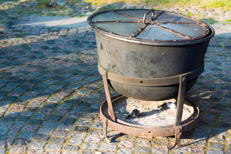 big ancient cauldron from iron or a boiler for cooking with a fire chamber for firewood and coalsの写真素材