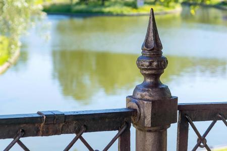 fragment of an ancient iron fence closeup in park in outdoor and a blank space against the pond or watersの写真素材